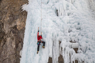 Frau klettert im Eispark in Lake City, Colorado, auf eine Klippe - CAVF79079