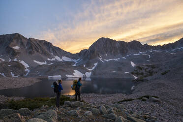 Women hikers watch sunset from Pierre Lakes, Elk Mountains, Colorado - CAVF79083