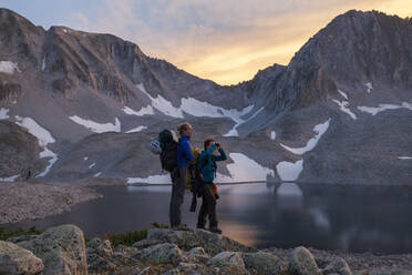 Women hikers watch sunset from Pierre Lakes, Elk Mountains, Colorado - CAVF79087