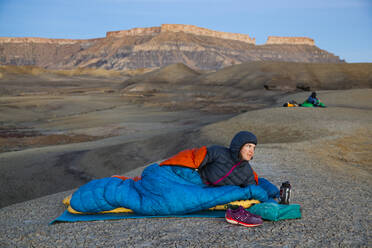 Menschen beobachten den Sonnenaufgang vom Camp in den Factory Butte Badlands, Utah - CAVF79104