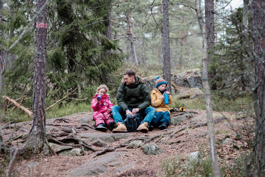 Dad having a snack with his kids whilst outside hiking - CAVF79217