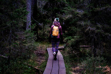 Frau geht entlang einer Promenade im Wald wandern im Winter - CAVF79220