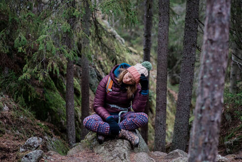 Frau auf einem Felsen sitzend, den Kopf in den Händen, während sie alleine wandert - CAVF79227