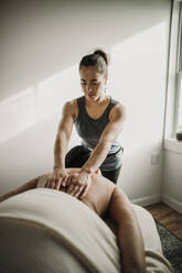 Massagetherapeutin legt ihre Hände auf den Rücken ihres Patienten - CAVF79238