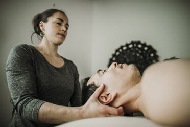 Male massage patient has neck worked on by female massage therapist - CAVF79244