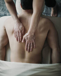 Nahaufnahme von weiblichen Händen auf männlichem Rücken auf Massagetisch von oben - CAVF79260