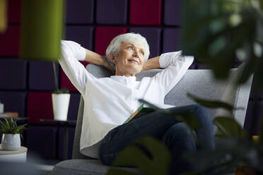 Porträt einer älteren Geschäftsfrau, die sich auf einem Liegestuhl entspannt - RBF07563