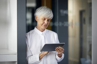 Porträt einer älteren Geschäftsfrau, die ein digitales Tablet im Büro benutzt - RBF07576