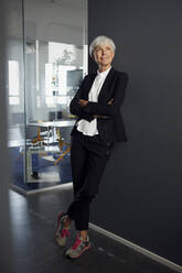 Porträt einer eleganten älteren Geschäftsfrau in Hosenanzug und Turnschuhen im Büro - RBF07592