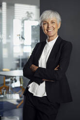 Portrait of smiling senior businesswoman wearing pantsuit in office - RBF07593