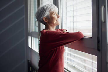 Porträt einer älteren Frau, die aus dem Fenster schaut - RBF07606