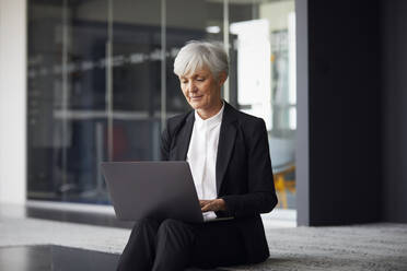 Porträt einer älteren Geschäftsfrau, die an einem Laptop arbeitet - RBF07611