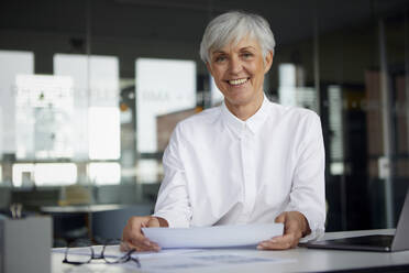 Porträt einer zufriedenen älteren Geschäftsfrau am Schreibtisch in ihrem Büro - RBF07621