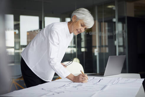 Portrait of architect working on construction plan in office - RBF07627
