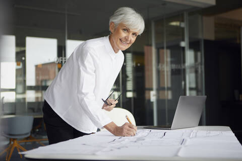 Porträt eines Architekten, der in einem Büro an einem Bauplan arbeitet, lizenzfreies Stockfoto