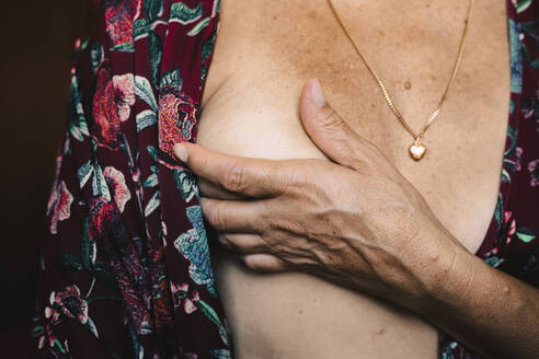 Nahaufnahme einer älteren Frau, die ihre Brust berührt - ERRF03510