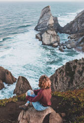 Young woman sitting on viewpoint at Praia da Ursa, Lisboa, Portugal - FVSF00178