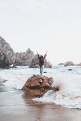 Young woman standing on rock at Praia da Ursa, Lisboa, Portugal - FVSF00191