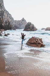 Junge Frau springt von einem Felsen am Praia da Ursa, Lisboa, Portugal - FVSF00194