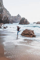 Young woman jumping from rock at Praia da Ursa, Lisboa, Portugal - FVSF00194