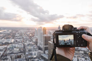 Deutschland, Hessen, Frankfurt, Hände einer Frau beim Fotografieren der Innenstadt bei Sonnenuntergang - AHSF02324