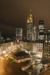 Germany, Hesse, Frankfurt, Illuminated town square at night with downtown skyscrapers in background - AHSF02337
