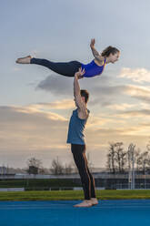 Young couple doing acrobatics at sunset - STSF02496