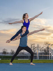 Young couple doing acrobatics at sunset - STSF02497