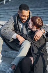 Happy young couple hugging on stairs in the city - MEUF00426