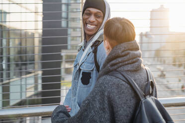 Happy young couple on a footbridge in the city at sunset - MEUF00461