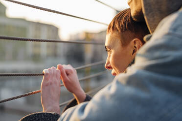 Verliebtes junges Paar auf einer Fußgängerbrücke bei Sonnenuntergang - MEUF00471