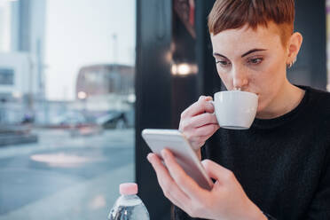 Rothaarige junge Frau benutzt Smartphone in einem Café - MEUF00482