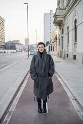 Portrait of young woman standing on bicycle lane in the city, Milan, Italy - MEUF00486