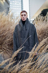 Portrait of young woman among grasses in the city - MEUF00493