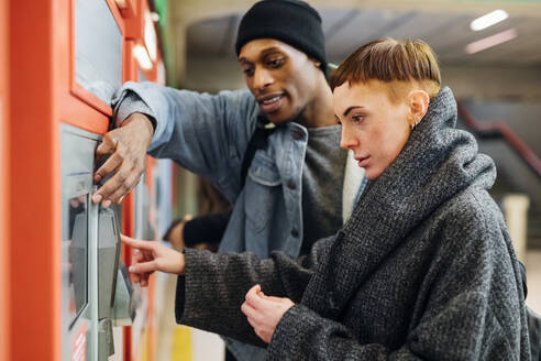 Young couple using ticket machine in the city - MEUF00503