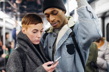 Young couple using smartphone on a subway - MEUF00505