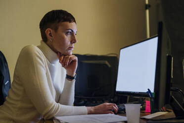 Rothaarige junge Frau an einem Computer am Schreibtisch - MEUF00517