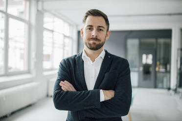 Portrait of brunette businessman arms crossed in office - GUSF03498