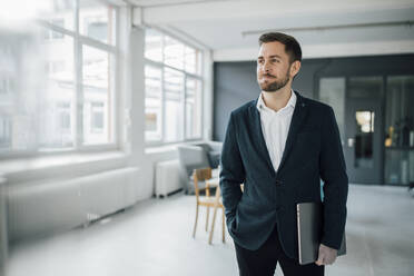 Businessman holding laptop in office - GUSF03506