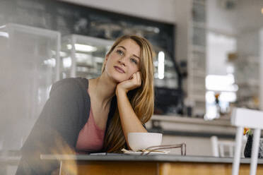 Porträt einer träumenden jungen Frau in einem Cafe - GUSF03524