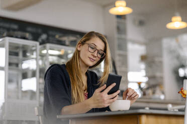 Junge Frau benutzt Smartphone in einem Café - GUSF03525