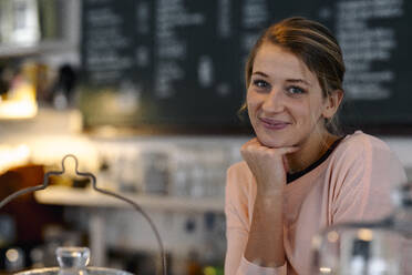 Porträt einer lächelnden jungen Frau in einem Cafe - GUSF03526