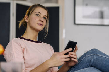 Portrait of relaxed young woman holding smartphone - GUSF03528