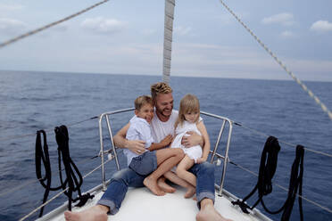 Father with his children sitting on boat deck during sailing trip - GMLF00098