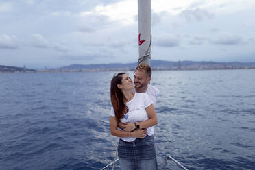 Lächelndes Paar, das sich während eines Segeltörns umarmt - GMLF00100