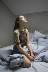 Woman with tattoo sitting on the bed. - CAVF79265