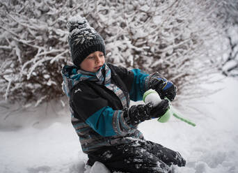 Junge macht Schneeball mit Schneeball machen Spielzeug auf Wintertag. - CAVF79315