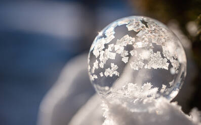 Nahaufnahme einer Seifenblase, die an einem Wintertag im Schnee gefriert. - CAVF79336