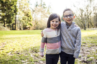 Brother and sister hugging outdoors. - CAVF79351