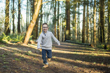 Young boy running through the forest. - CAVF79356